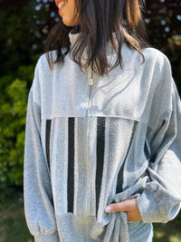 Person wearing a gray fleece jacket with black stripes outdoors