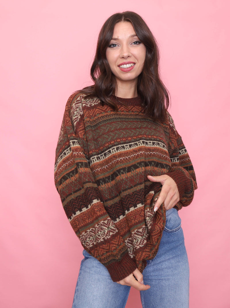 Model wearing a vintage 90s fair isle jumper in earthy rust and brown tones with Nordic-style knit pattern.

