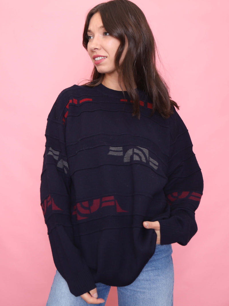 Model wearing a vintage navy knitted jumper with red and grey pattern – unisex 90s oversized sweater.

