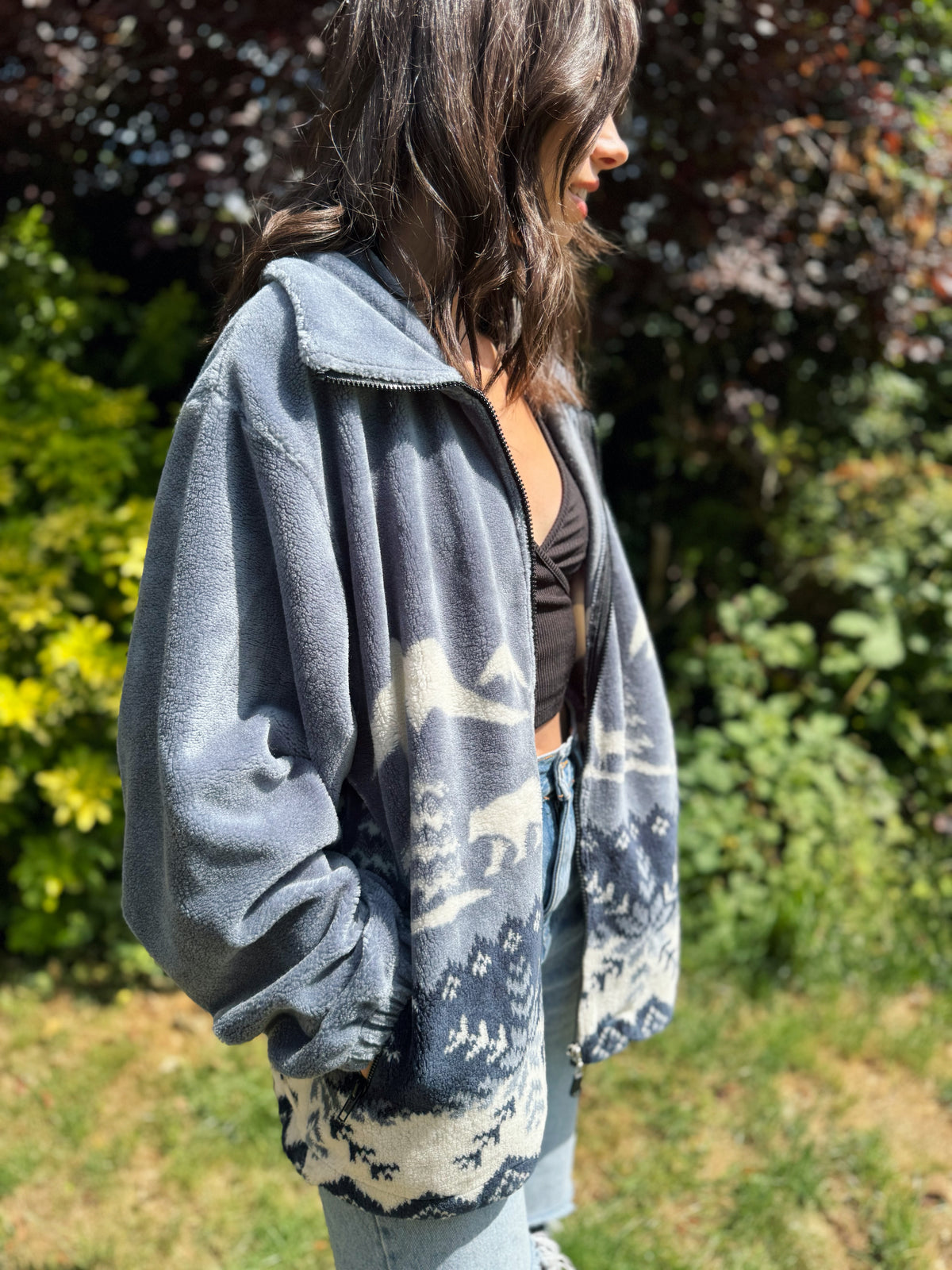 Woman wearing a vintage grey-blue teddy fleece jacket with polar bear forest pattern, cosy winter zip-up style

