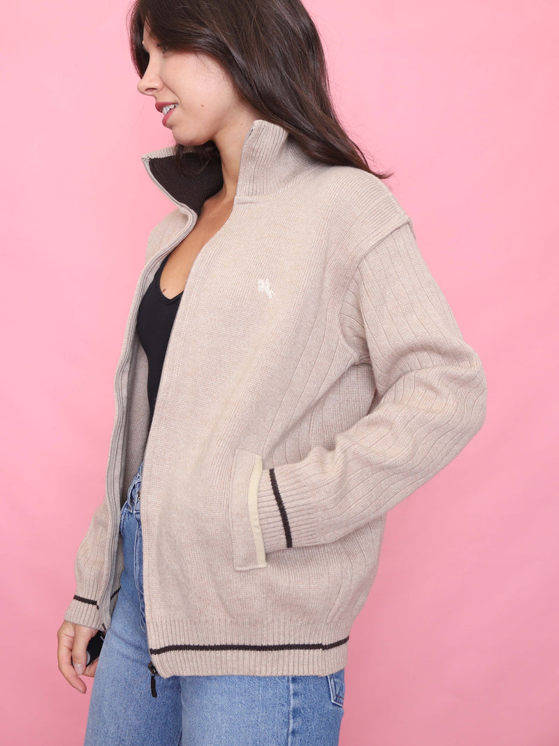 Model wearing a vintage neutral zip-up knit cardigan with ribbed texture, black trim, and a cosy unisex fit – ideal autumn wardrobe staple.