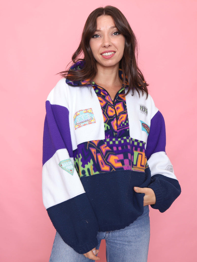 Model wearing bold multicoloured 90s-style vintage fleece pullover with patchwork and 1/4 zip

