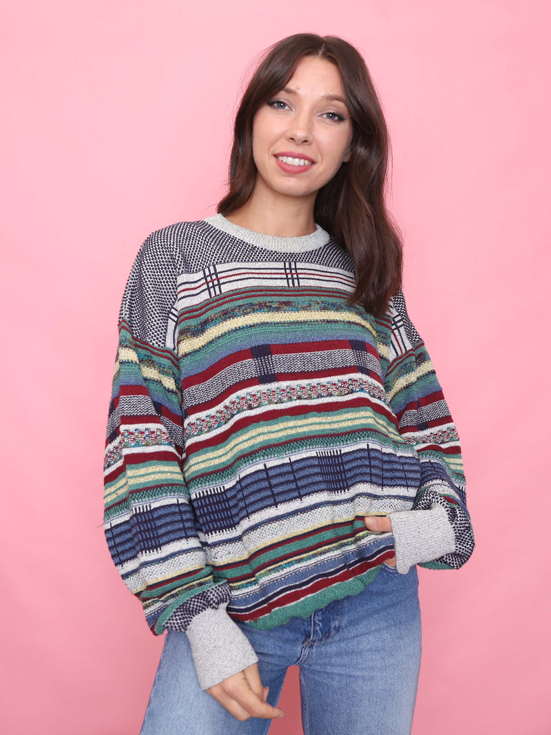 Model wearing a vintage 90s multicolour striped knit jumper with plaid accents and oversized fit.

