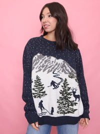 Woman wearing a navy vintage ski scene jumper with snowy mountain and skier pattern

