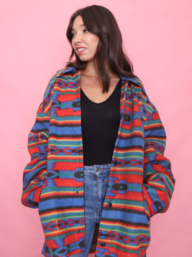 Model wearing a bold multi-colour vintage fleece jacket with Aztec-style print and popper button fastening – cosy oversized outerwear.