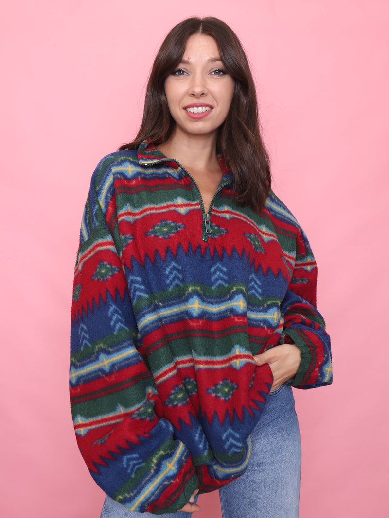 Model wearing a vintage 1/4 zip fleece with Aztec print in red, blue and green tones. Cosy unisex outdoorswear
