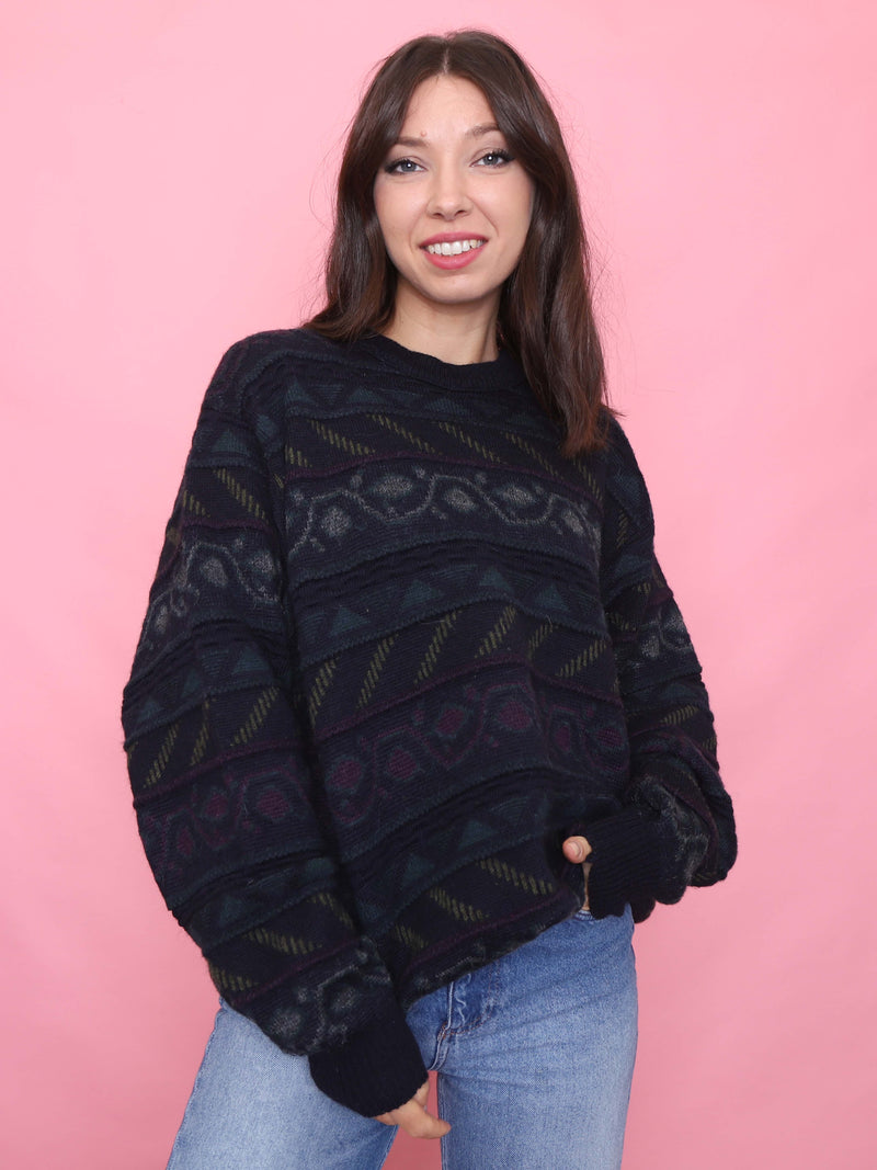 Model wearing a vintage black knit jumper with geometric pattern in muted green and burgundy tones, perfect for autumn layering