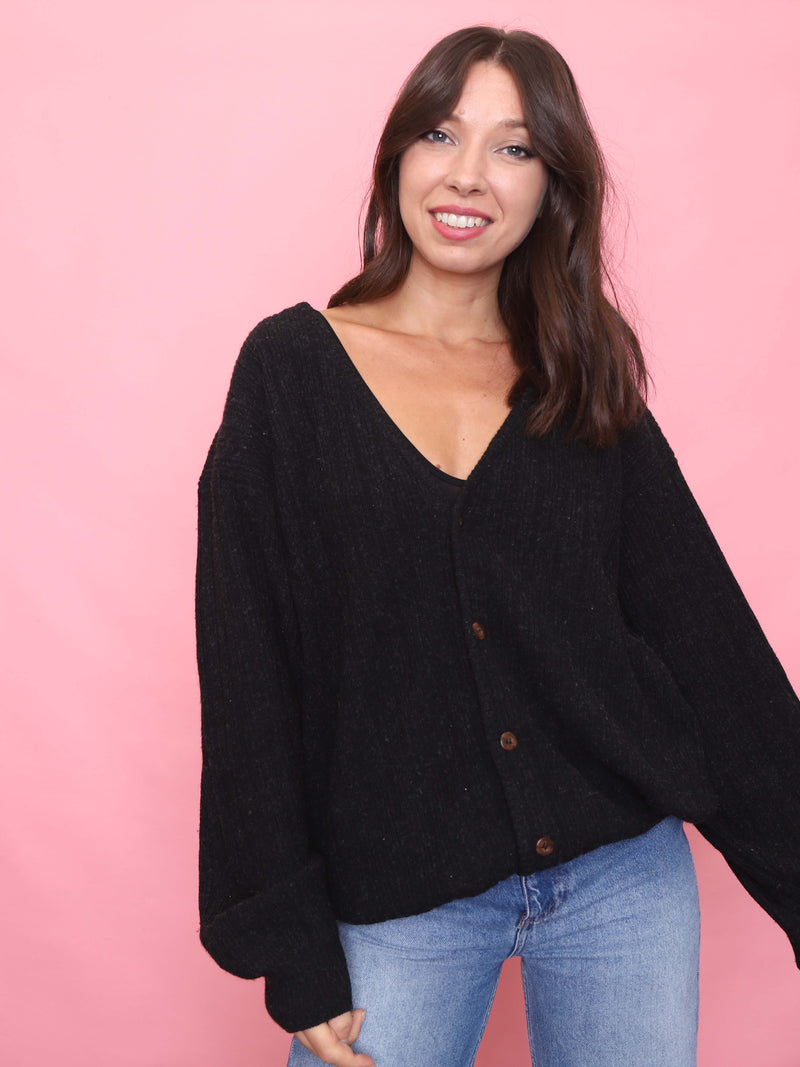 Model wearing vintage black ribbed knit cardigan with brown button