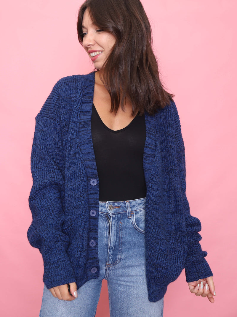 Model wearing a chunky vintage knit cardigan in cobalt blue with button-up front and slouchy fit, styled with light-wash jeans.