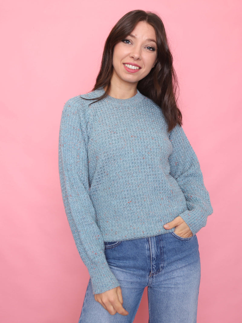 Model wearing a soft blue vintage knit jumper with multicoloured flecks and ribbed cuffs, styled for cosy winter days