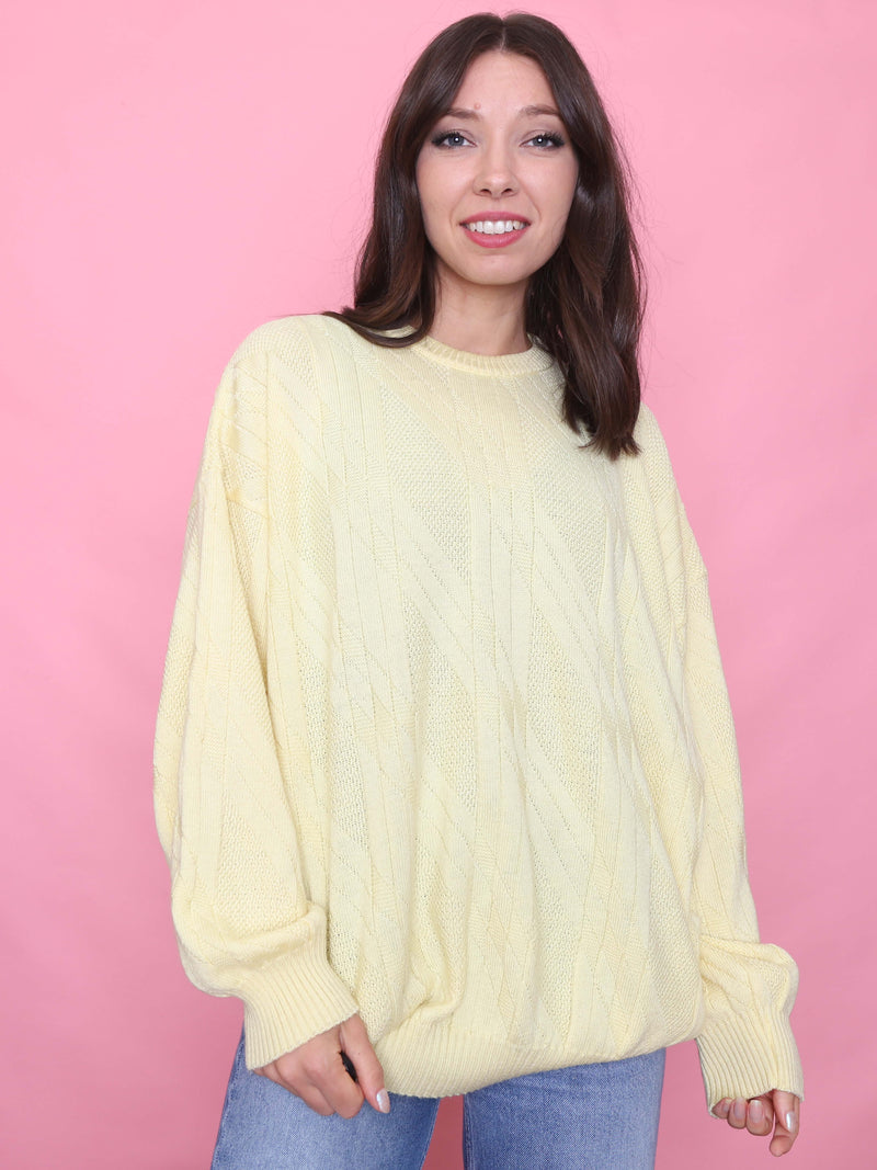 Woman wearing a vintage buttercream cable knit jumper styled for autumn with light denim

