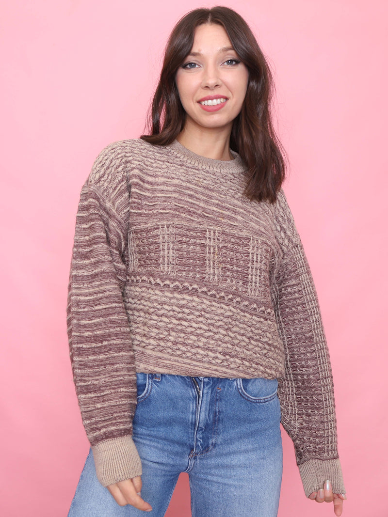 Woman wearing a patterned sweater and jeans against a pink background