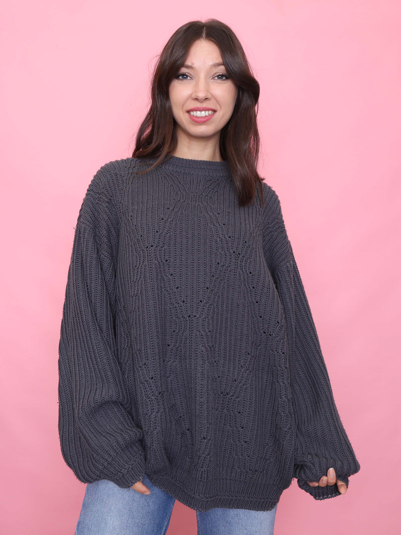 Model wearing a vintage charcoal grey chunky knit jumper with relaxed fit, styled with blue denim jeans

