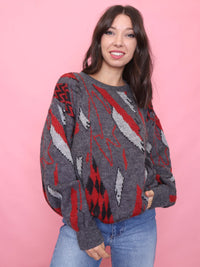 Woman wearing a vintage charcoal grey jumper with red and black geometric pattern styled for cosy autumn fashion