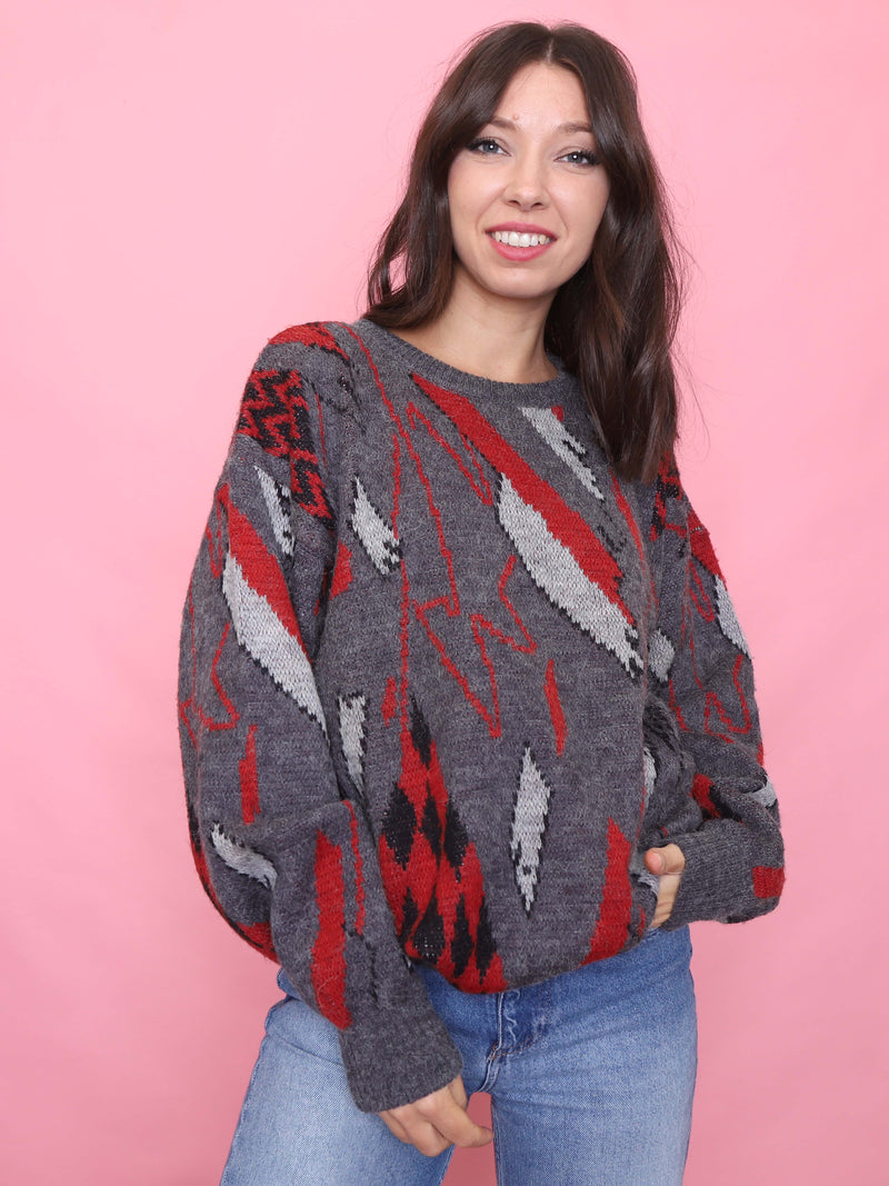 Woman wearing a vintage charcoal grey jumper with red and black geometric pattern styled for cosy autumn fashion