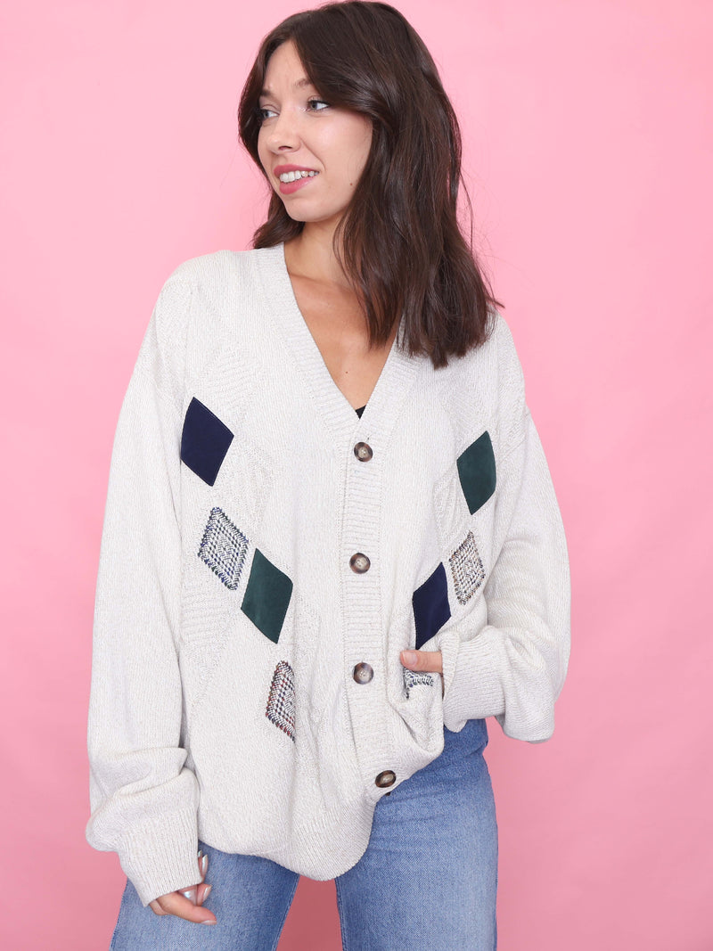 Model wearing a vintage cream knit cardigan with geometric diamond patch detailing in a relaxed oversized fit.