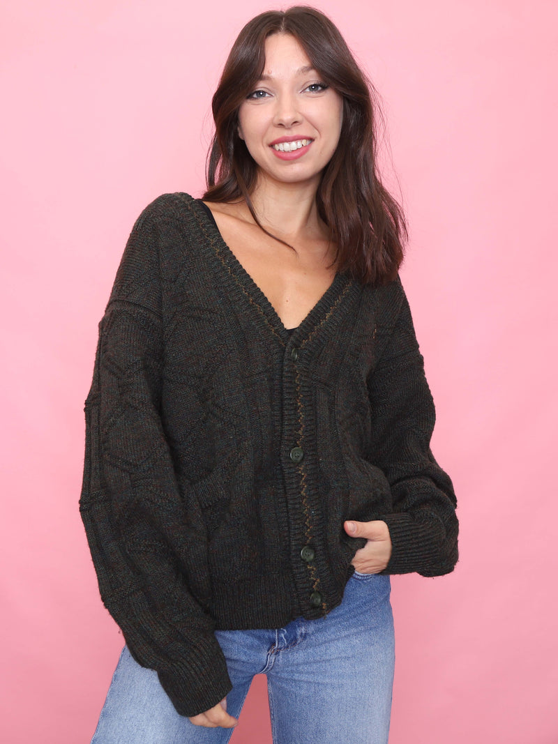 Model wearing a deep forest green vintage knit cardigan with chunky texture and button-up front, styled with high-waisted denim.
