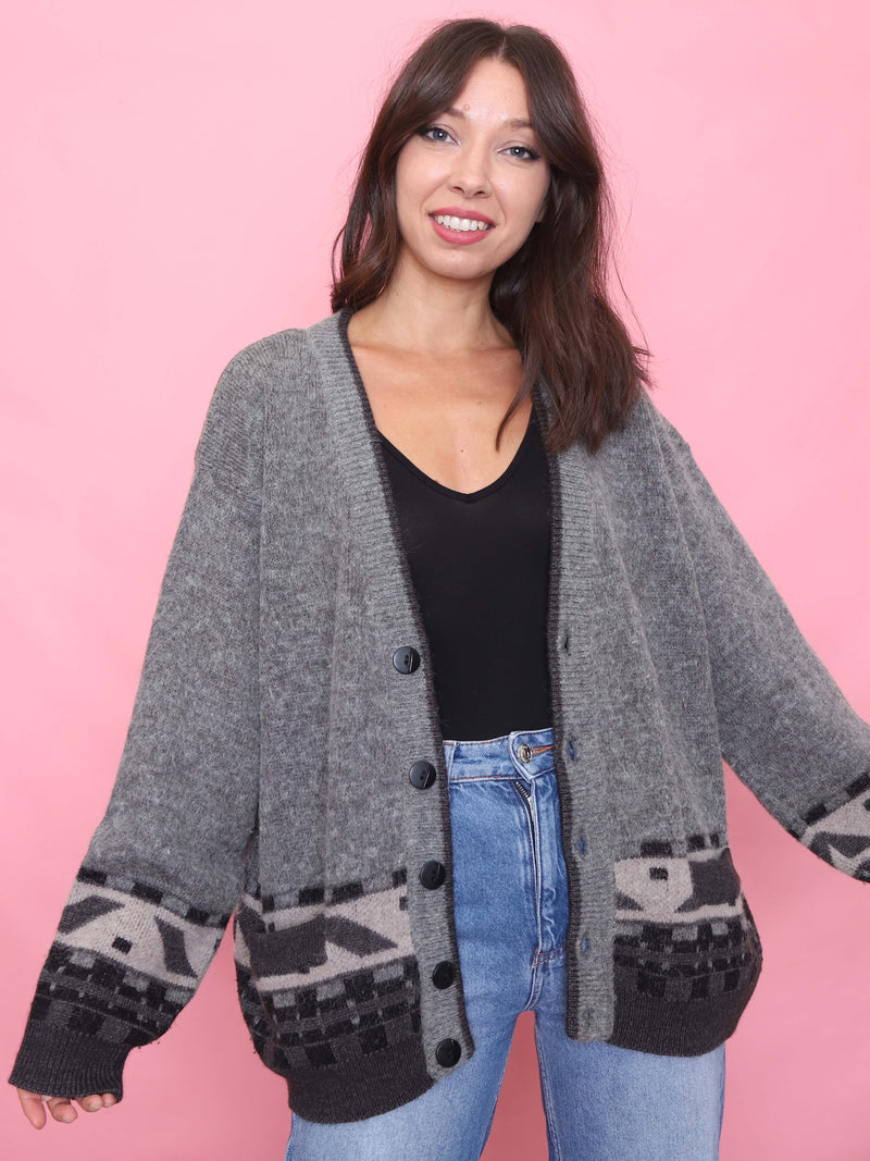 Model wearing a vintage oversized grey cardigan with bold black and grey geometric knit pattern around the hem and cuffs.