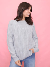 Model wearing a 90s vintage light grey knit jumper with a textured front pattern – minimalist unisex sweater.