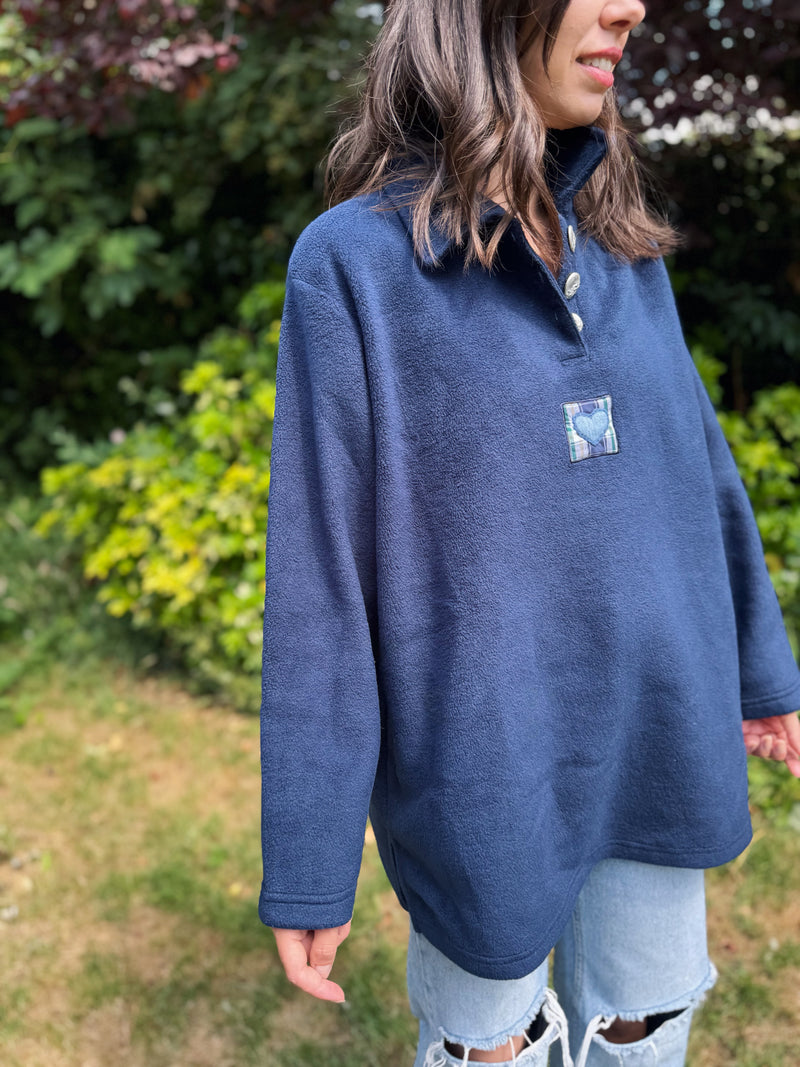 Model wearing a navy blue vintage 1/4 button fleece with patch heart detail outdoors