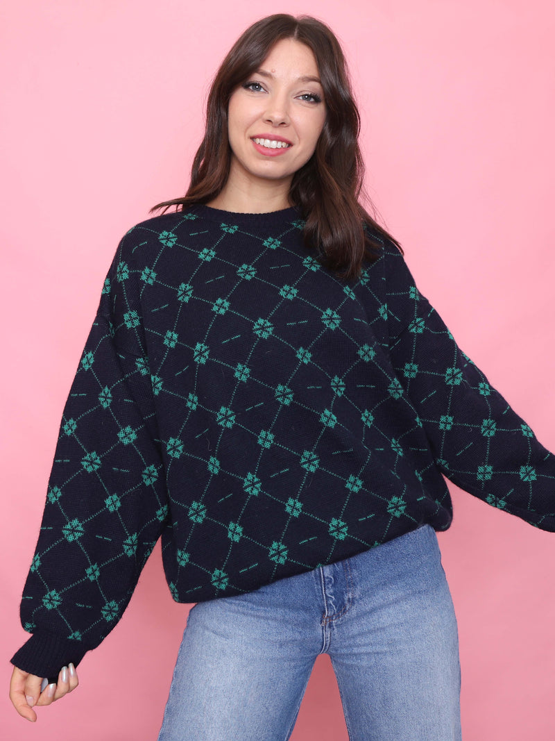 Model wearing a navy vintage jumper with green geometric pattern and relaxed fit, styled with light blue jeans

