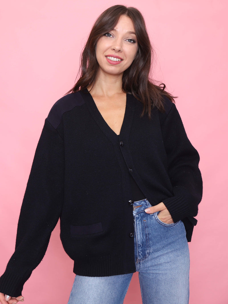 Model wearing a vintage navy knit cardigan with tonal shoulder panels, button-up front, and slouchy fit styled with denim.
