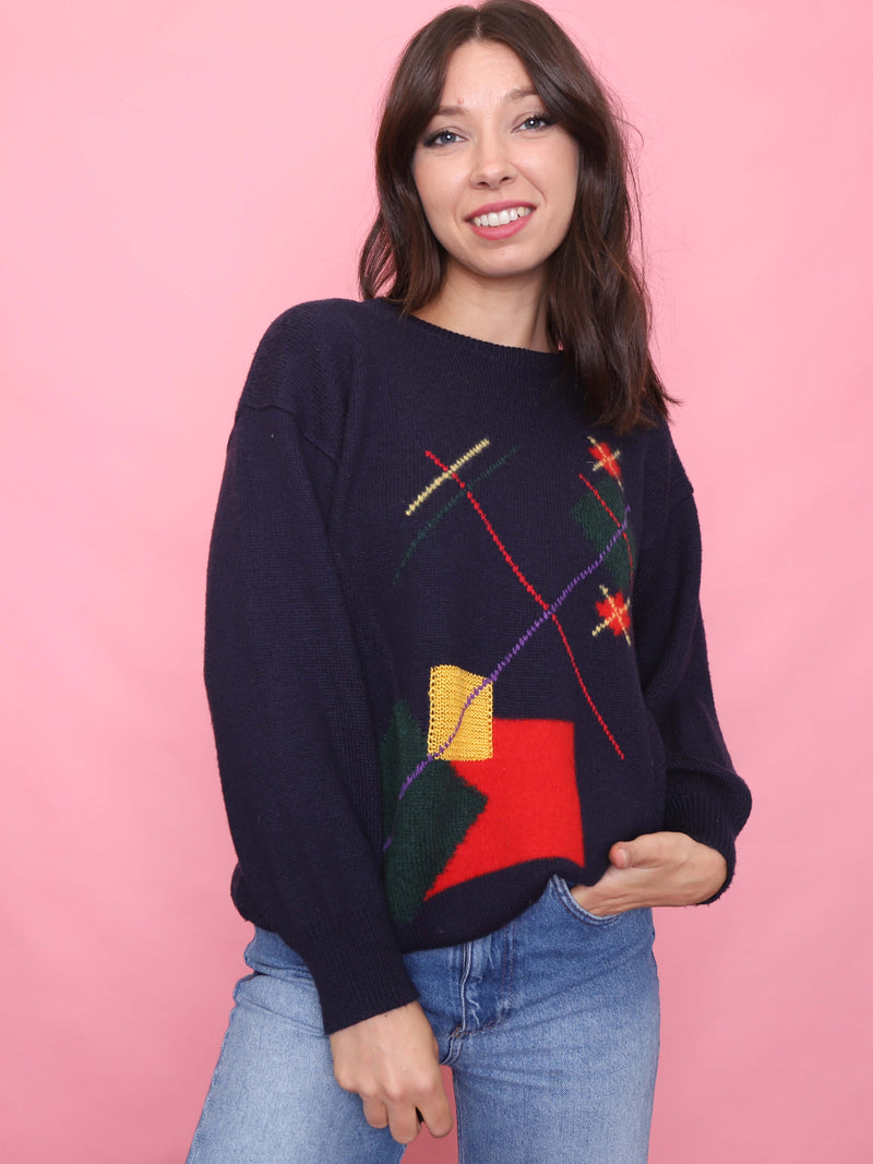 Woman wearing a vintage navy knit jumper with bold retro geometric pattern in red, yellow, green and purple

