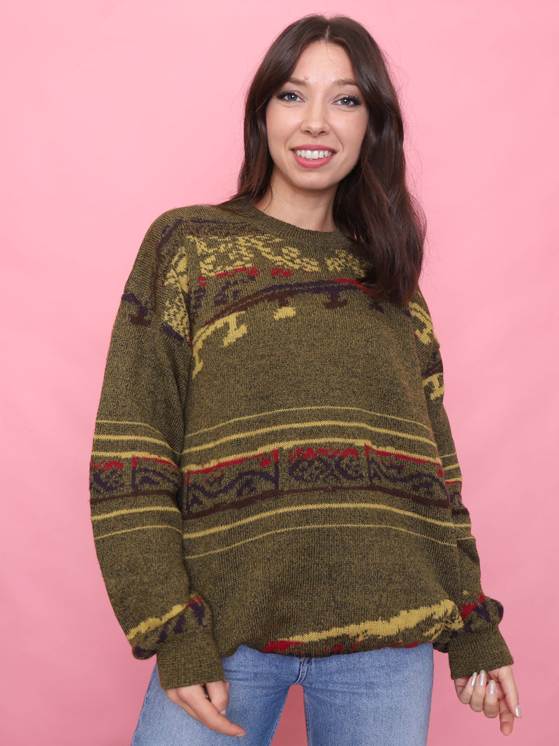 Woman wearing a vintage olive green jumper with abstract autumnal pattern in red, mustard, and navy

