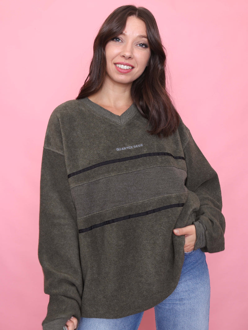 Model wearing a vintage olive green Quarterdeck fleece sweatshirt with embroidered logo and stripe detailing – relaxed outdoor pullover style.