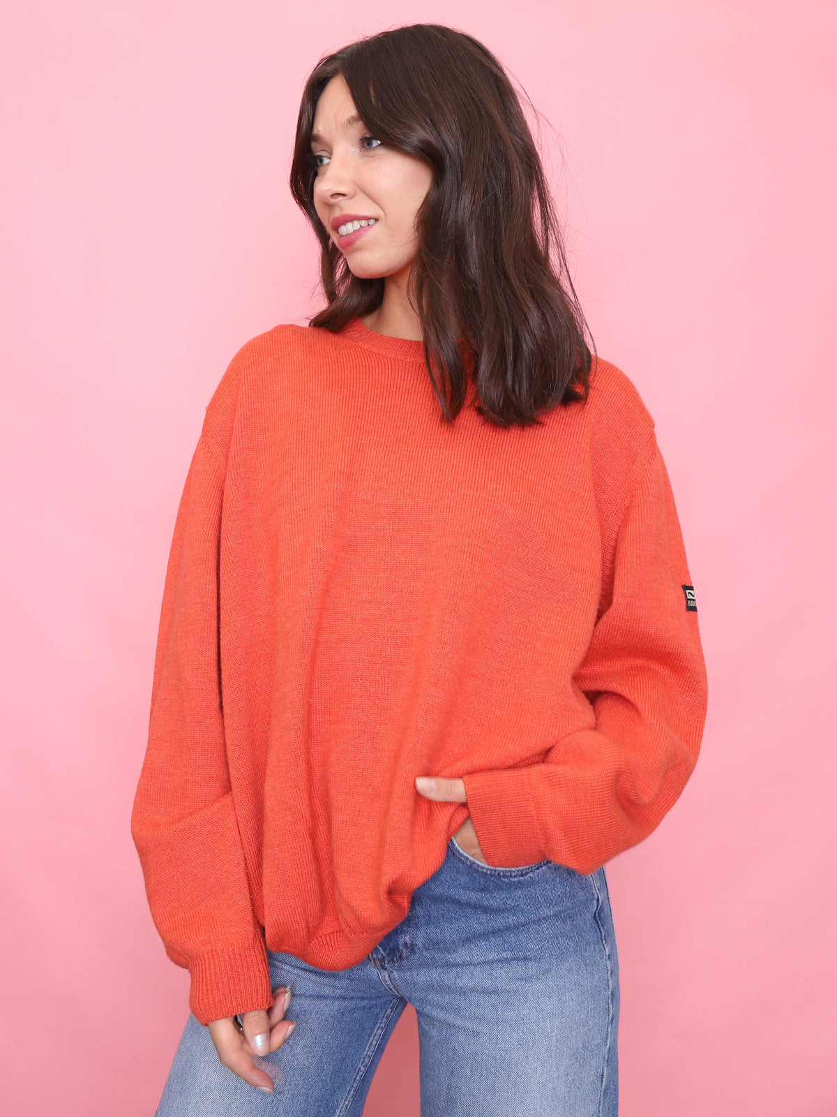 Model wearing a vibrant orange oversized vintage jumper with ribbed cuffs and hem from the 90s.

