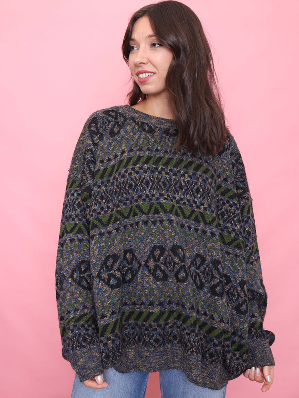Model wearing a vintage patterned knitted jumper in blue, green, and black – oversized unisex 90s style.

