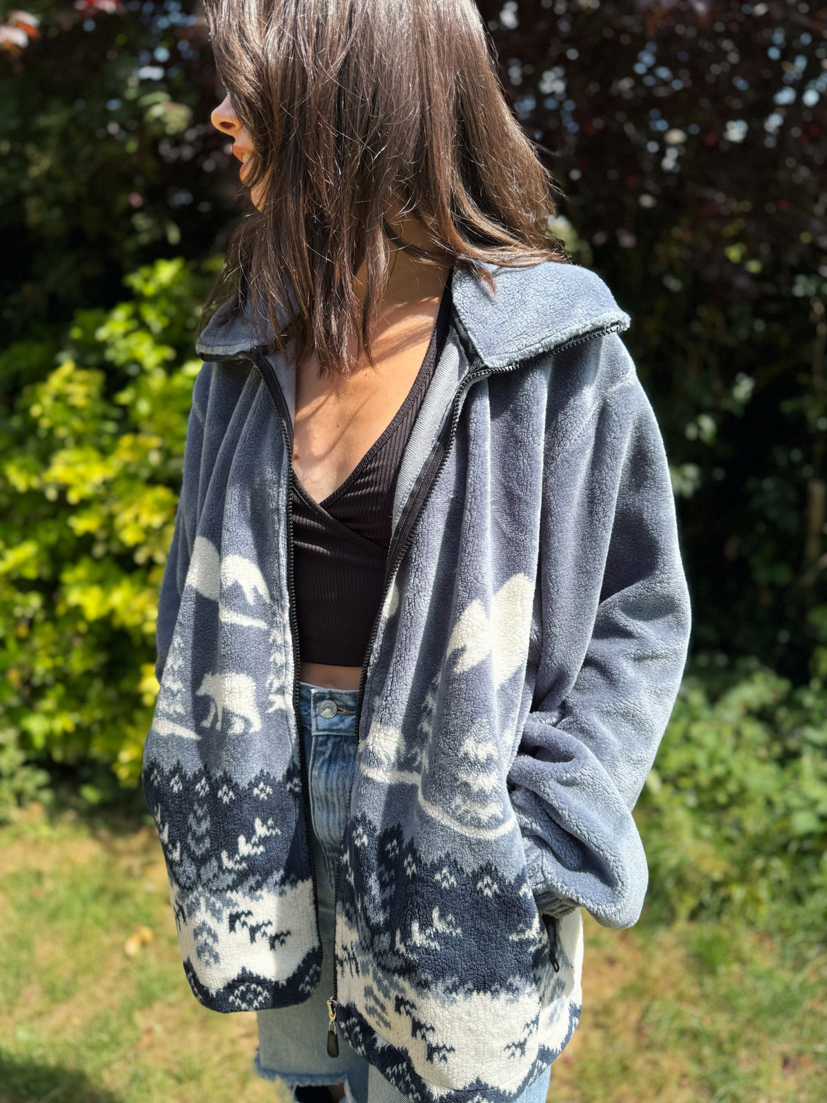 Woman wearing a vintage grey-blue teddy fleece jacket with polar bear forest pattern, cosy winter zip-up style

