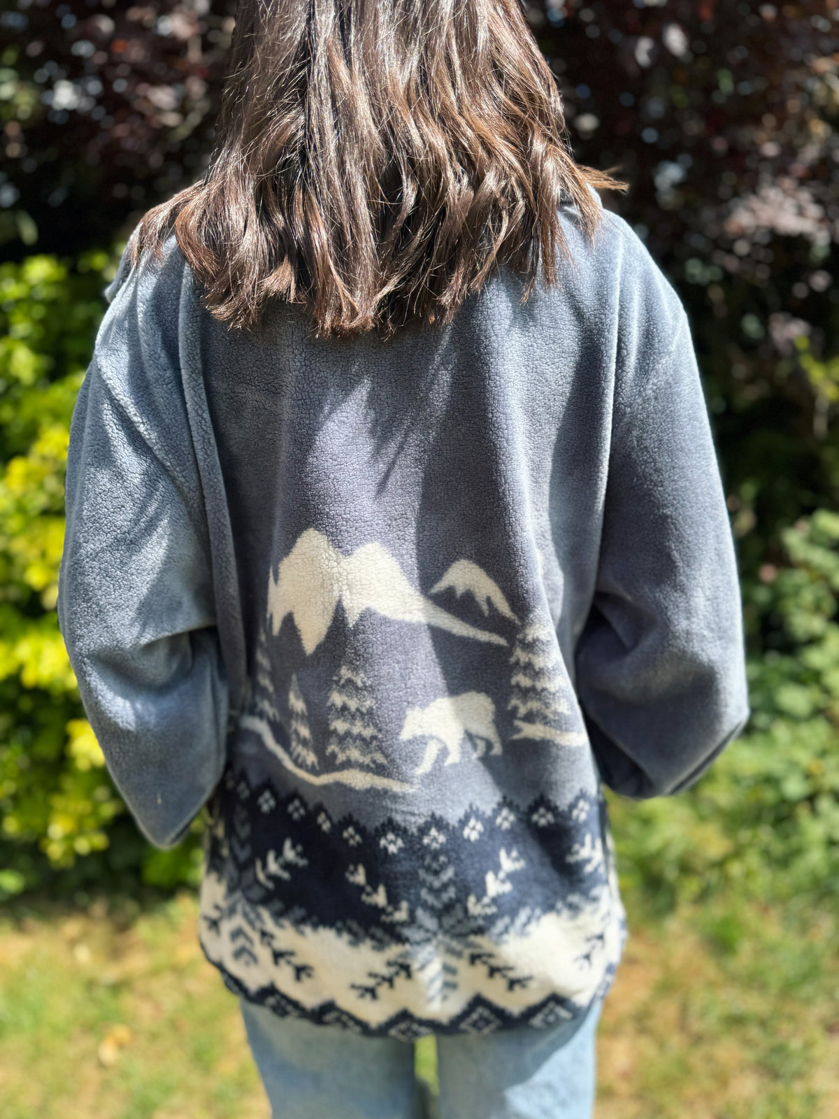 Woman wearing a vintage grey-blue teddy fleece jacket with polar bear forest pattern, cosy winter zip-up style

