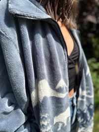 Person wearing a gray fleece jacket with bear designs outdoors