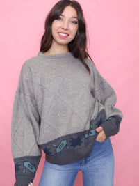 Woman wearing a vintage taupe knit jumper with diamond texture and Aztec-style border, styled with jeans