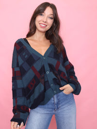 Model wearing a vintage oversized cardigan with teal, navy, and burgundy abstract pattern. 