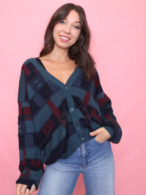 Model wearing a vintage oversized cardigan with teal, navy, and burgundy abstract pattern. 